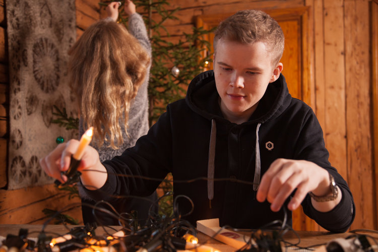 Pojke och flicka som klär julgranen med ljus