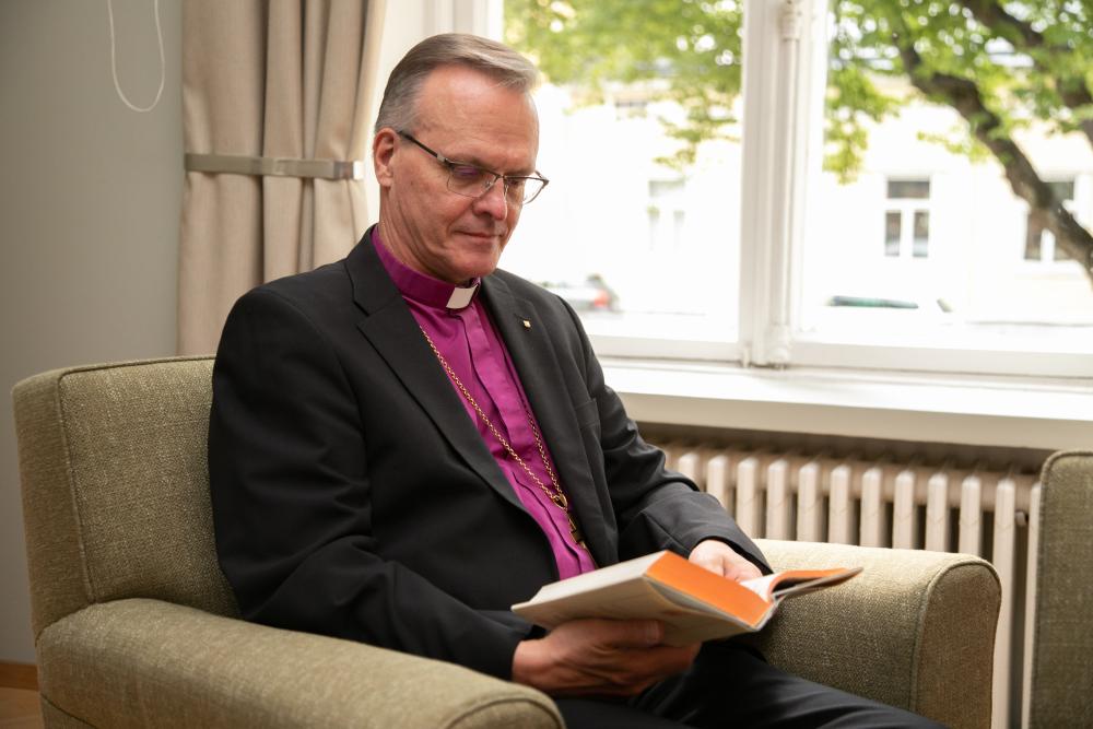Arkkipiispa Tapio Luoma istuu Raamattu kädessään.