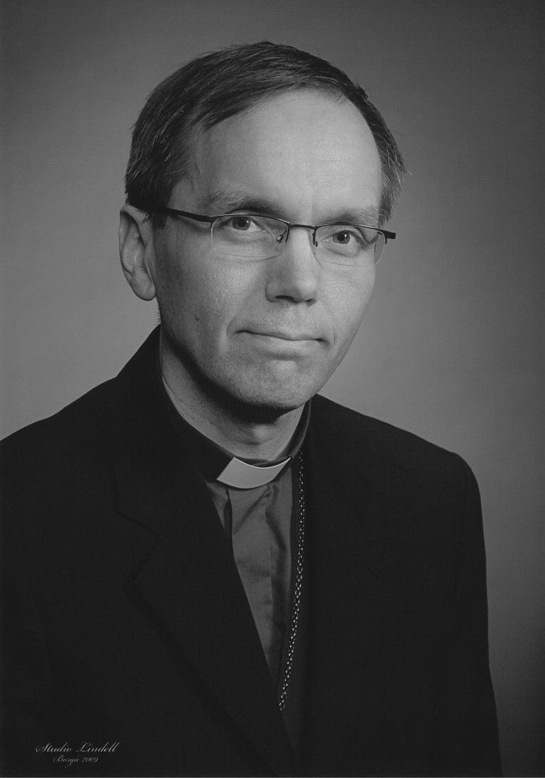 Mörkhårig Björn Vikström med glasögon iklädd biskopsskjorta och mörk kavaj. Biskopskorset skymtar under kavaj.
