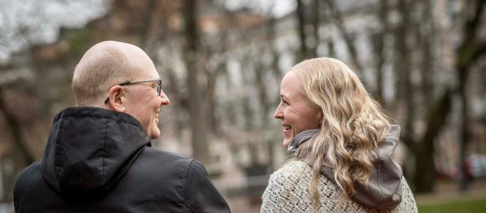 Lähikuvassa mies ja nainen katsovat toisiaan. Taustalla syksyinen kaupunki.