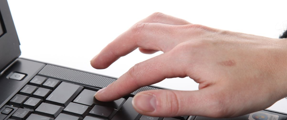 Käsi joka napauttaa kannettavan tietokoneen enter-painiketta.