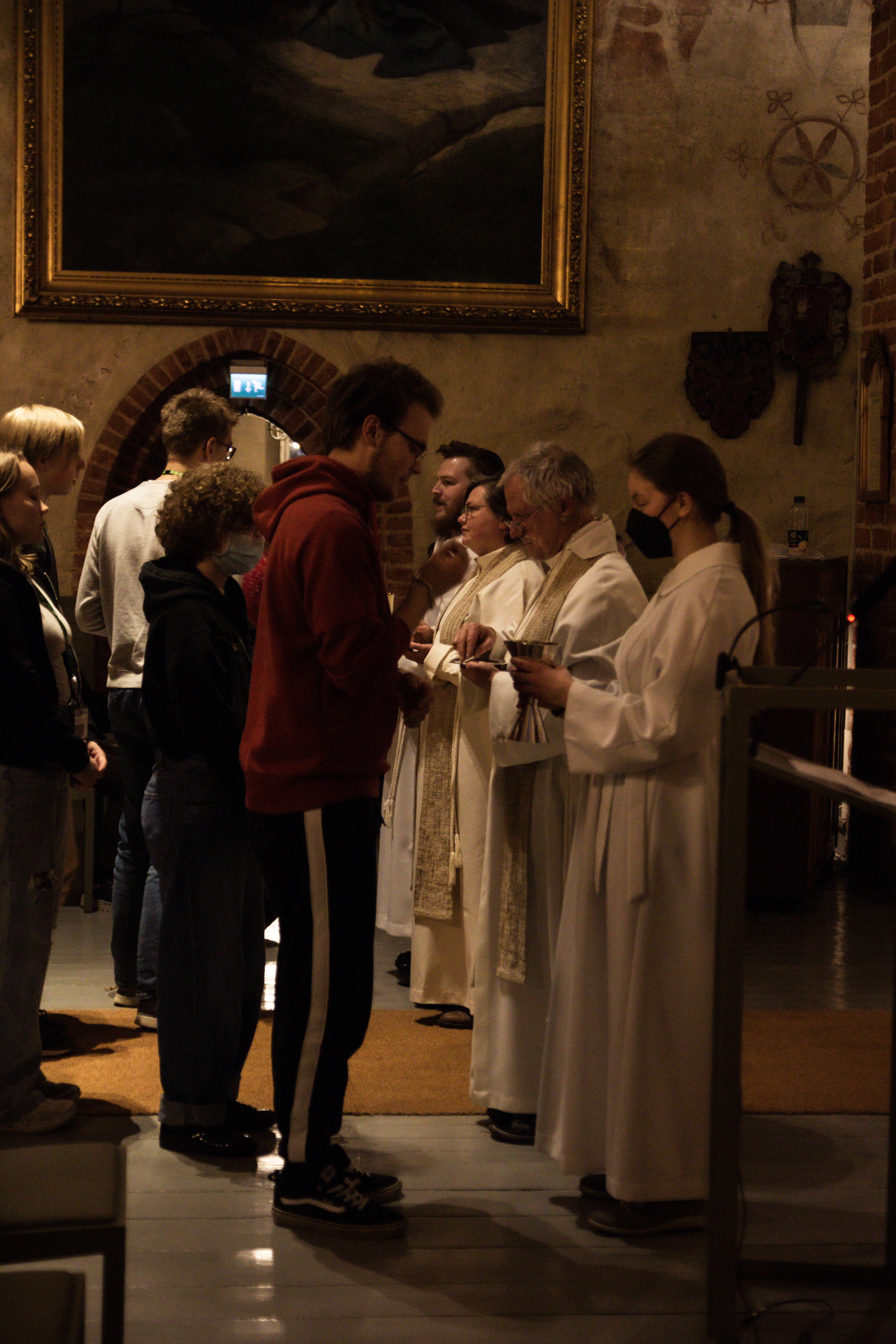 Ungdomar tar emot nattvard från präster och unga assistenter.