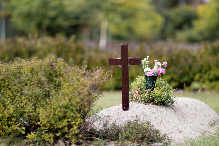 Nyligen täckt grav med träkors och blommor på