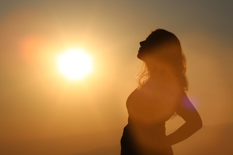 Gravid kvinna som silhuett mot solen.
