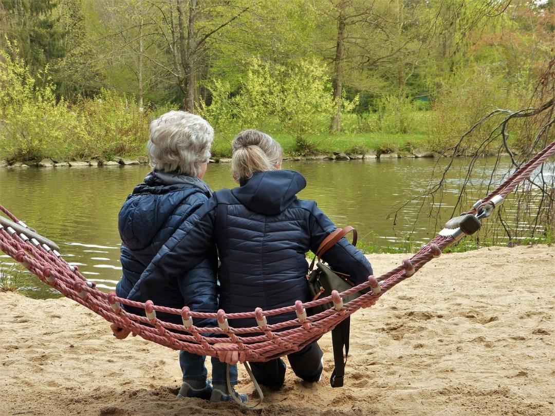 Mor och dotter i hängmatta, tittar ut över en damm.