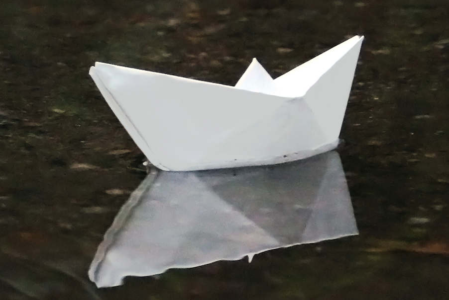 Pappersbåt flyter på vattnet.