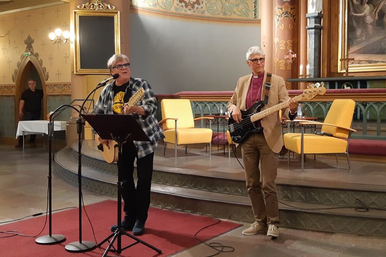 Mikko Alatalo soittaa kitaraa ja piispa Matti Repo bassoa Keski-Porin kirkon alttarin edessä.