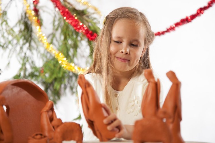 Flicka som leker med julkrubba i lera