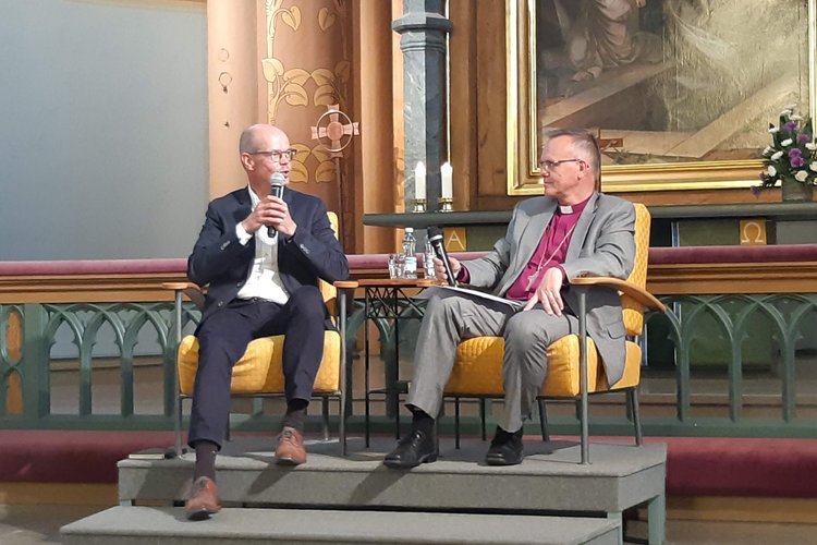 Opetushallituksen pääjohtaja ja arkkipiispa Tapio Luoma istuvat Keski-Porin kirkon alttarin ääressä keskustelemassa opetuksesta ja elämästä SuomiAreenan piispan iltahetkessä.