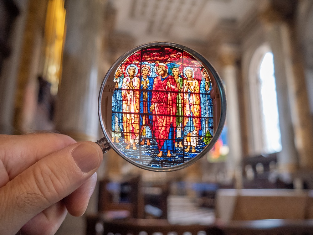 Kirkossa oleva värikäs lasimaalaus, jota katsotaan suurennuslasin läpi.