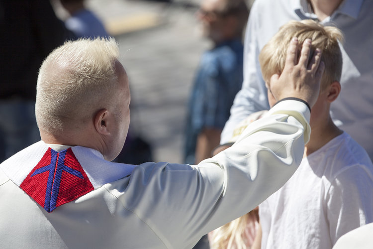 Präst välsignar en pojke med handpåläggning.