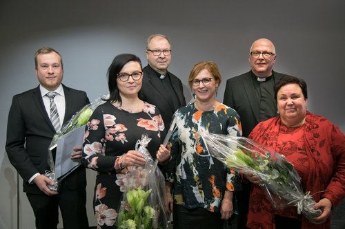 Kirteko-palkitut kukat kädessä. Edessä kolme naista ja takana kolme miestä.