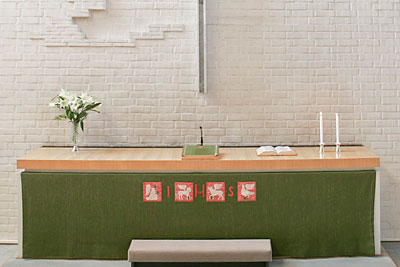 Ett grönt altare med två ljus och en liten vit blomma på.