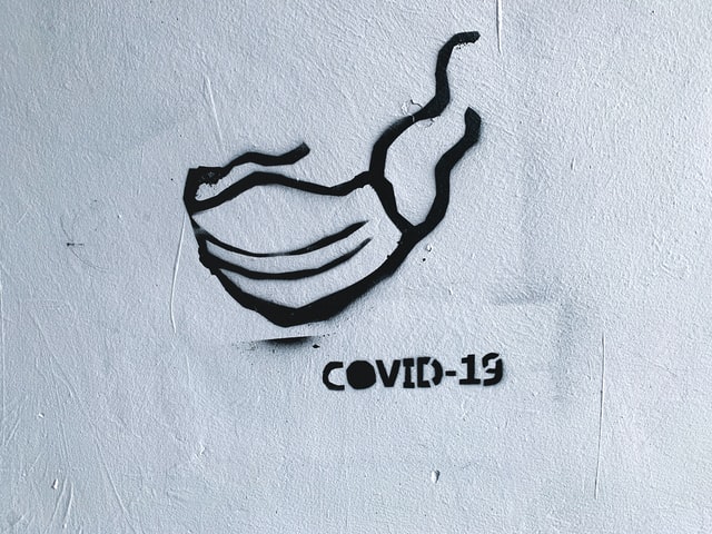 Valkoiselle betoniseinälle maalattu musta teksti, jossa lukee Covid-19. Kuvaaja Adam Nieścioruk, Unsplash.com.