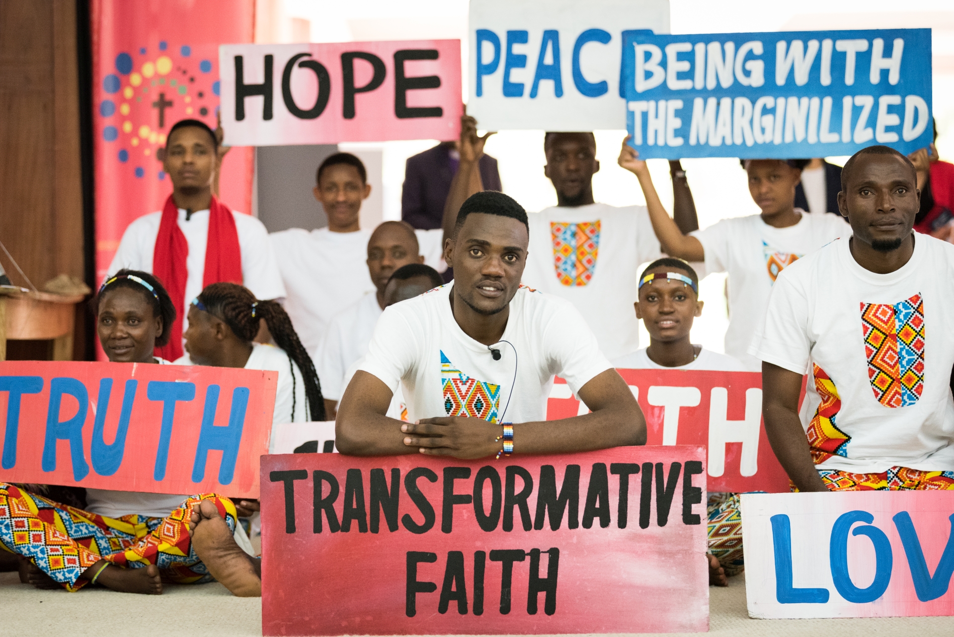 Nuoret pitävät kylttejä, joissa sanat: truht, love, hope, transformative faith, peace, being with the marginalized