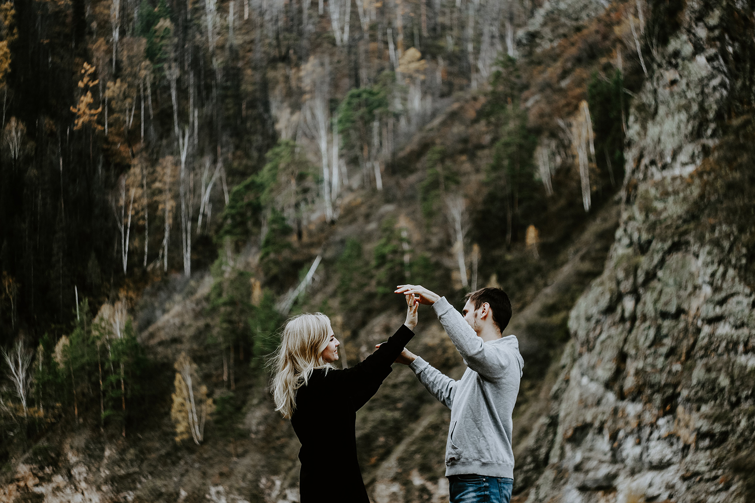 Pariskunta onnellisena vuoren juurella kädet toisiaan vasten. Kuvaaja: pure julia / unsplash.com