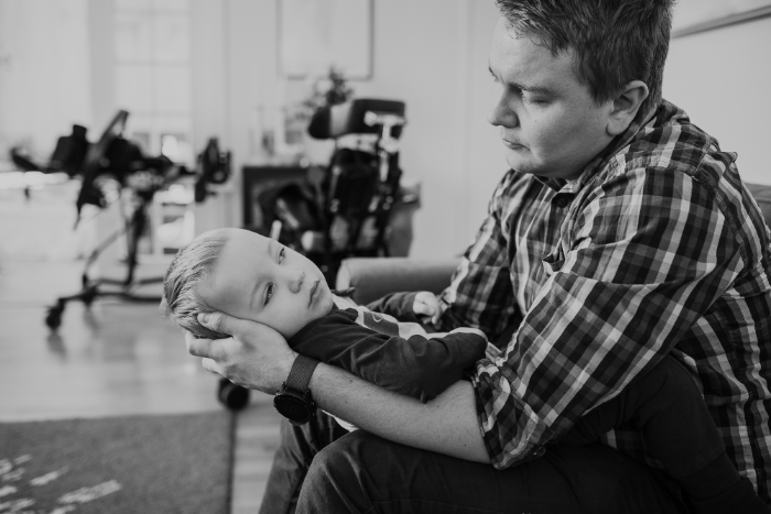 Pappa Nicklas håller sin son Oliver i famnen. Han stöder Olivers huvud och blickarna möts