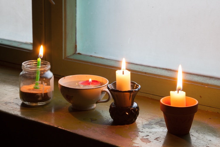 Neljä erilaista kynttilää palamassa ikkualaudalla.