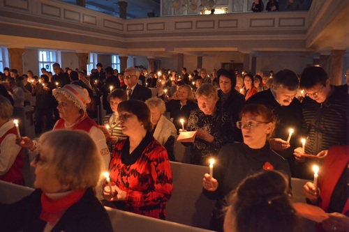 Kirkko täynnä ihmisiä, joilla on kynttilät kädessään.