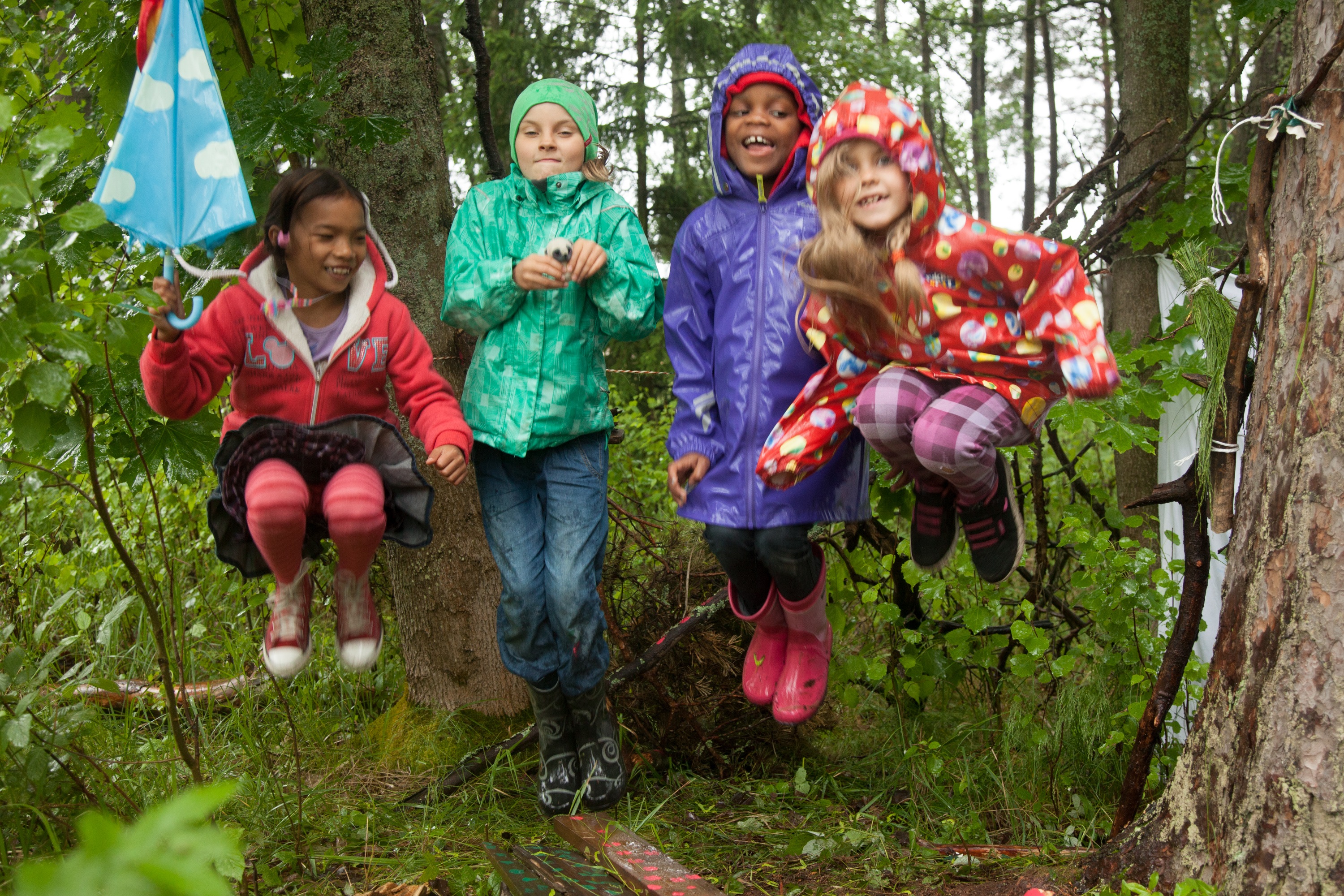 Fyra barn som hoppar i en skog