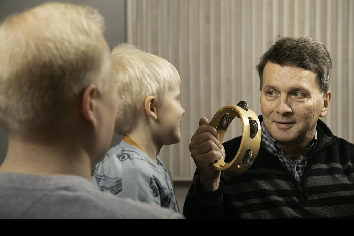 Två vuxna och ett barn spelar på tamburin