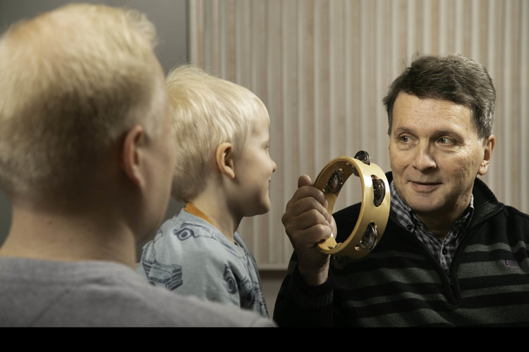 Två vuxna och ett barn spelar på tamburin