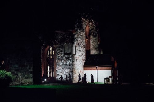 Pimeässä illassa kirkon ulkopuolella ihmisten siluetteja.