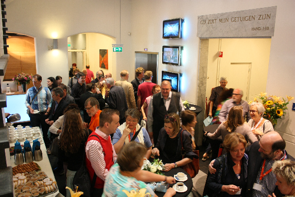 People stranding and drinking coffee in a hall.