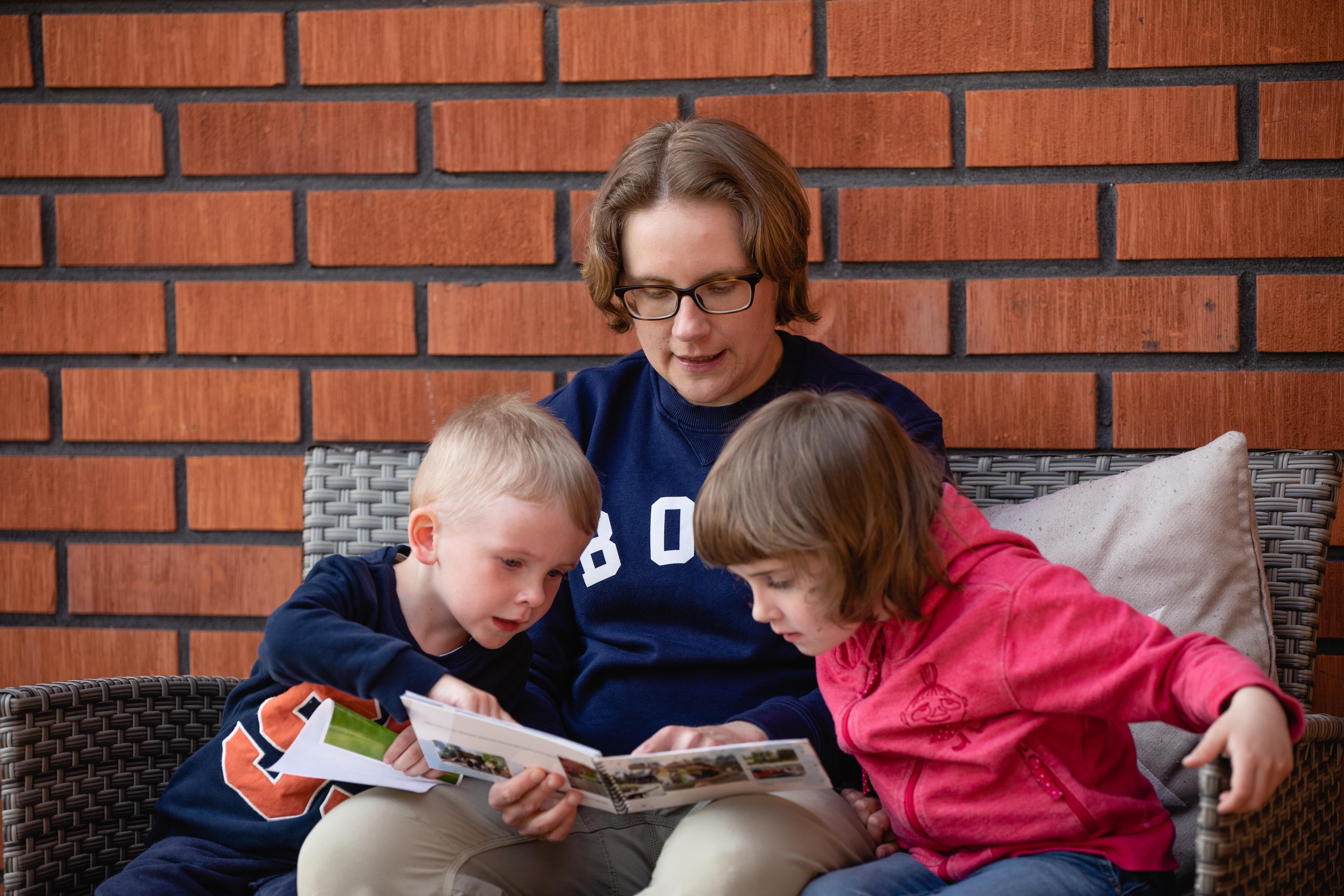 Fadder läser bok tillsammans med två fadderbarn.
