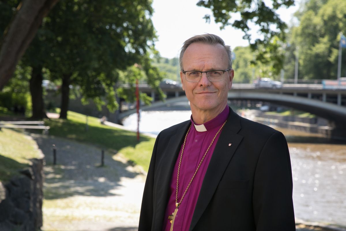 Arkkipiispa Tapio Luoma seisoo jalkakäytävällä joen rannalla.