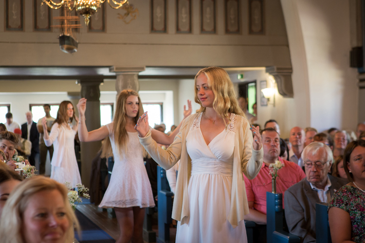 Tre konfirmander i mittgången under en konfirmation