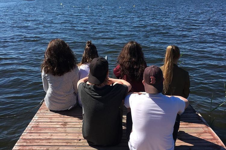 Ungdomar sitter på en brygga och tittar ut över havet