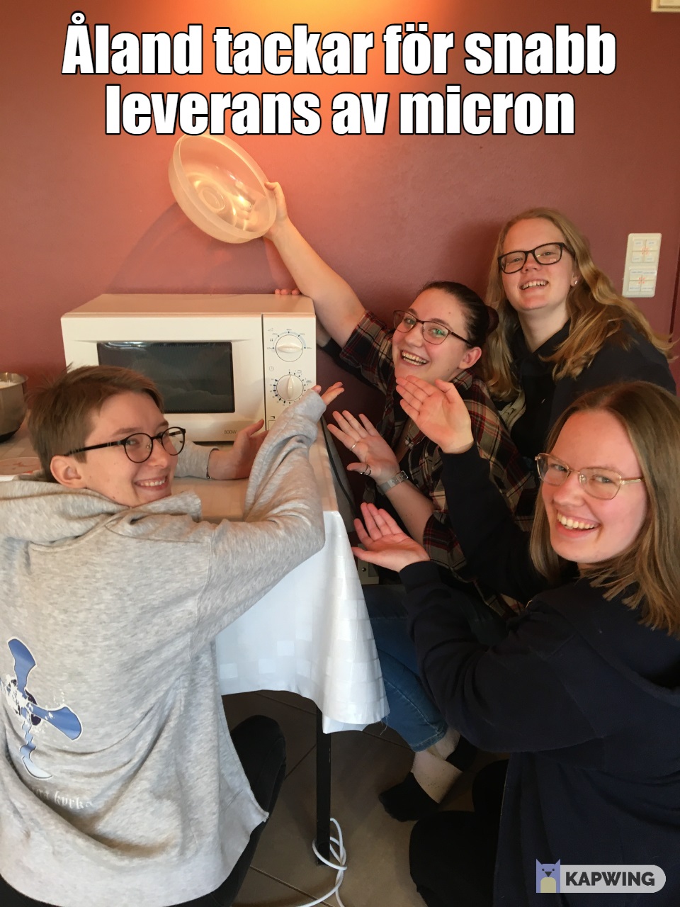 Bild på fyra ungdomar kring en mikrovågsugn och texten: Åland tackar för snabb leverans av mikron.