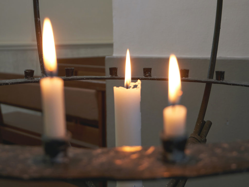 Kuvassa kolme kynttilää lähetyskynttelikössä.