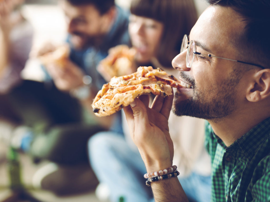 Män och kvinnor som äter pizza tillsammans