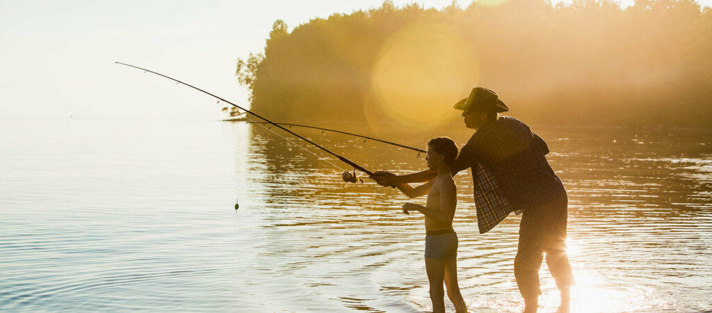 Mies ja poika kalastavat järvessä vierekkäin. 