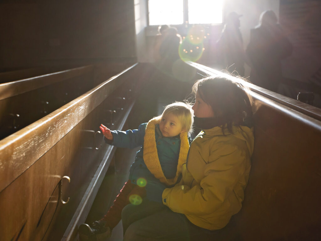 Två barn sitter i kyrkbänk.