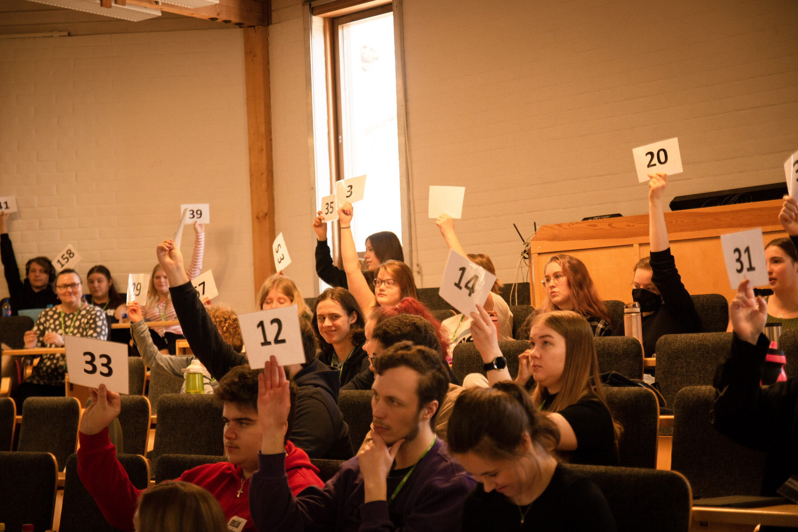 Ungdomar i ett auditorium håller upp sifferkort.