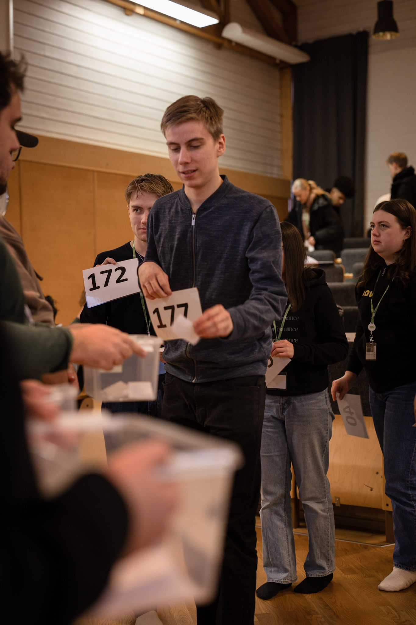 Ungdomar köar med sifferkort för att lägga en röstsedel i en låda.