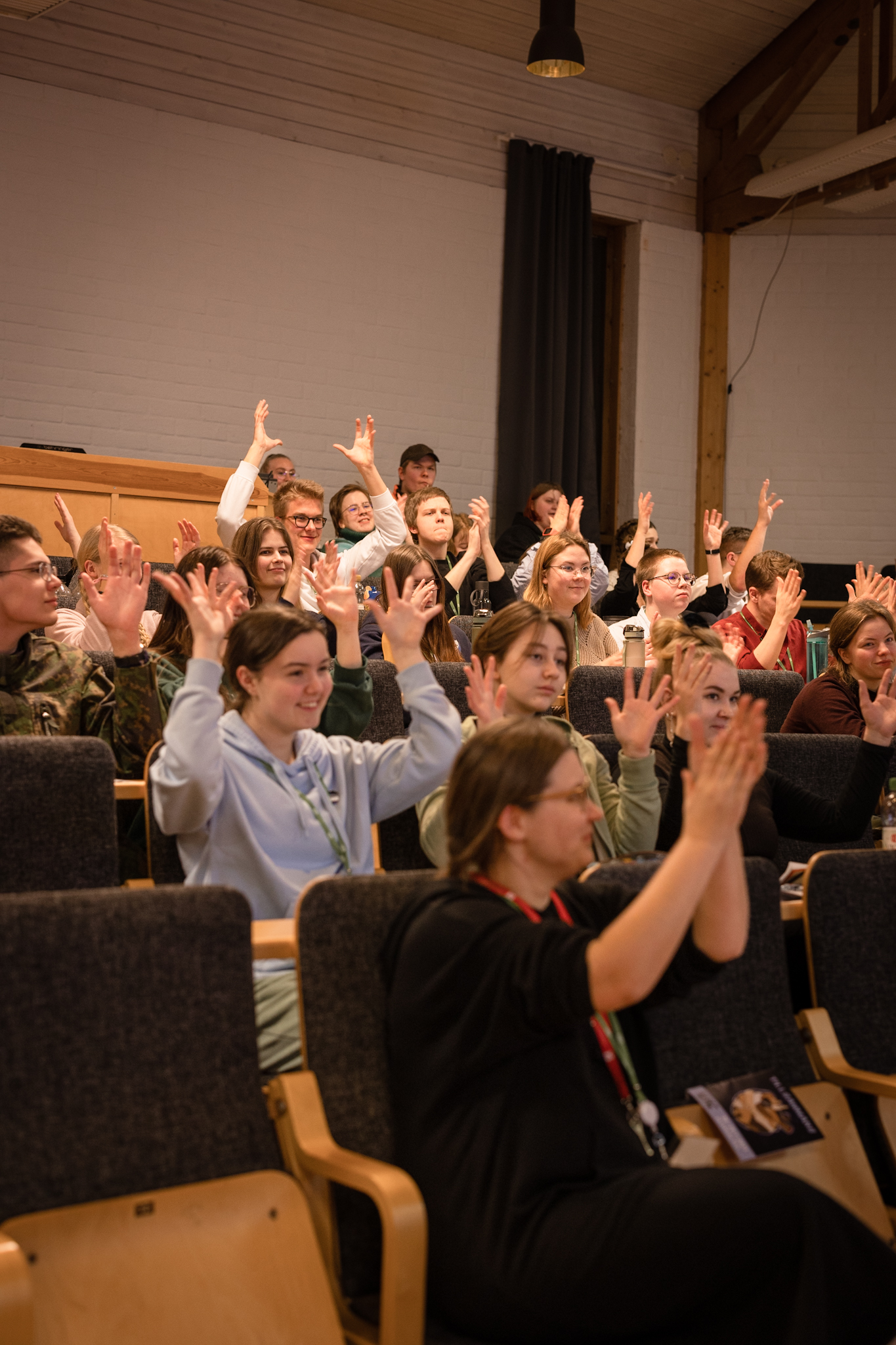 Ungdomar i ett auditorium applåderar på teckenspråk.
