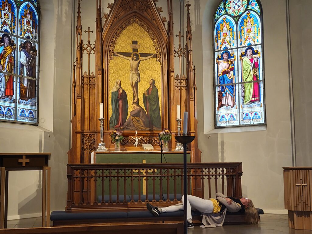 Ihminen makaa kirkkosalissa alttaripenkillä. Hän on löytänyt kirkosta turvallisen tilan.