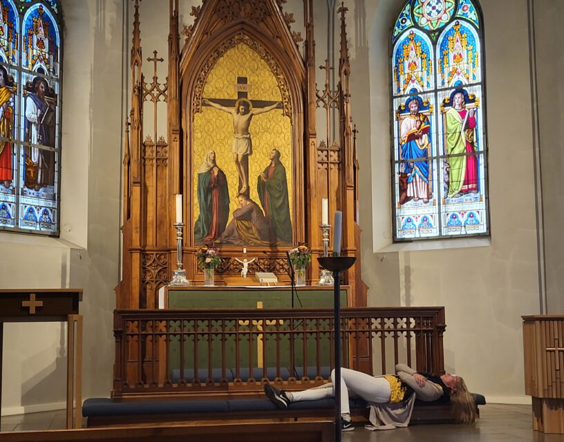 Ihminen makaa kirkkosalissa alttaripenkillä. Hän on löytänyt kirkosta turvallisen tilan.