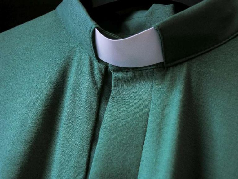 Diakoniatyöntekijän vihreä virkapaita, jossa kauluksessa samanlainen valkoinen kaistale kuin papin virkapaidassa.