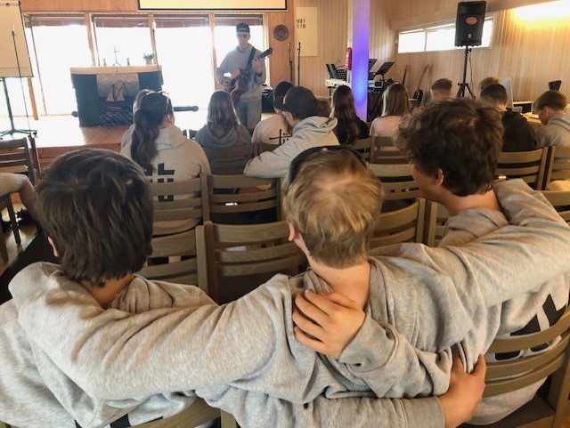 Tre pojkar som håller om varandra under en musikstund.