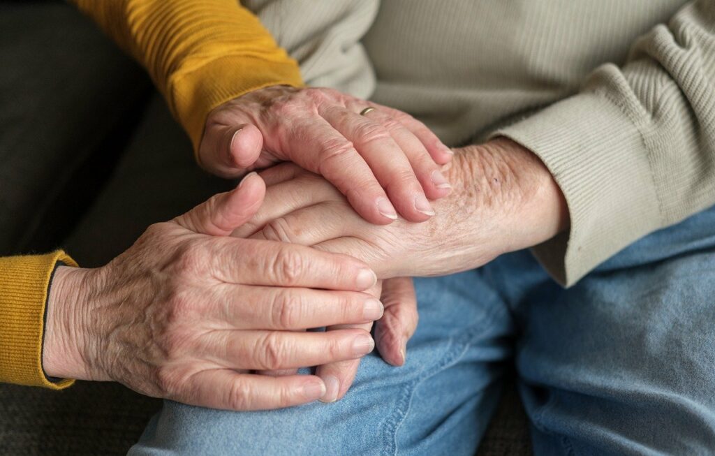 Kaksi ikä-ihmistä pitää toisiaan kädestä.