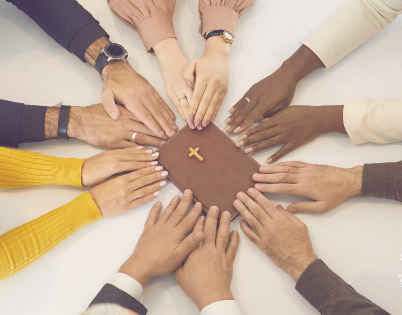 Ihmisten käsiä ja keskellä Raamattu