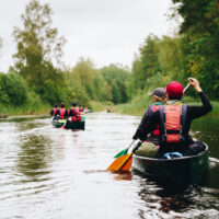 Scouter paddlar längs å.