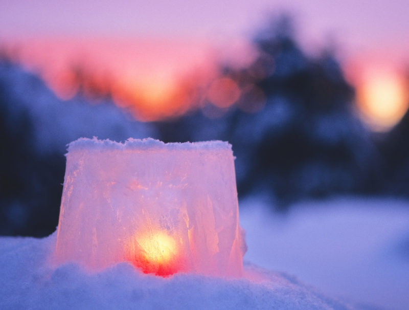 Ljus lyser i en islykta i vintrig solnedgång.