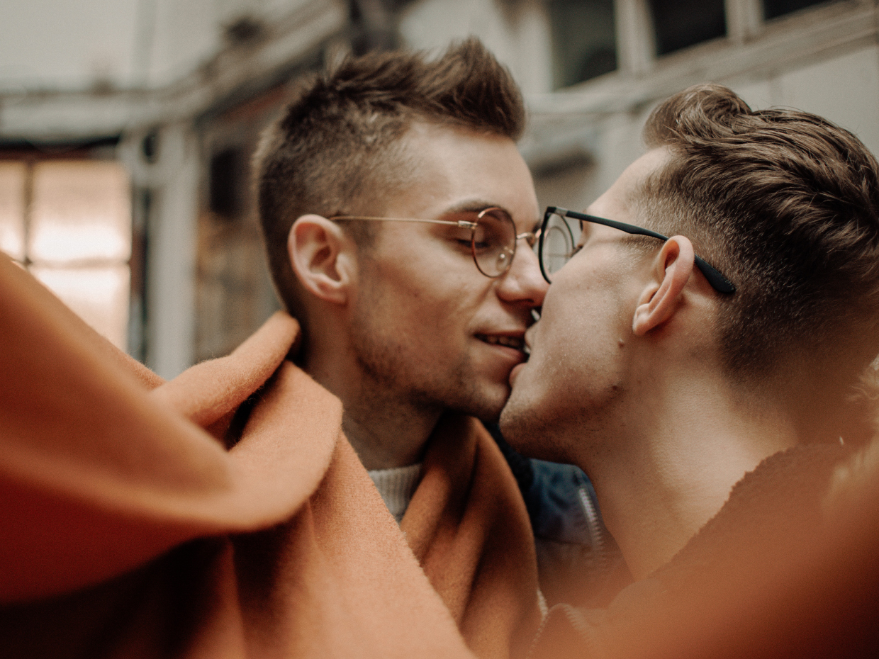 Två unga män kysser varandra.