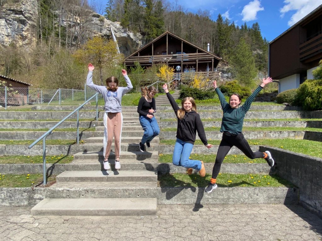 People jumping in front of a cottage.